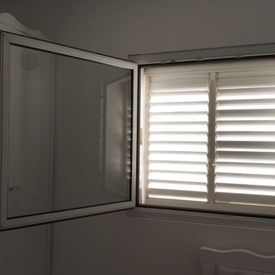 תריסים לבנים פתוחים למחצה בחלון