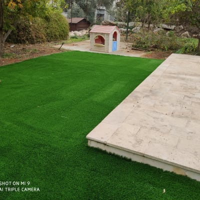 דשא סינתטי ירוק ליד שביל אבן בגינה
