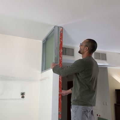 אדם מתקין מסגרת מתכת בקיר במהלך שיפוץ