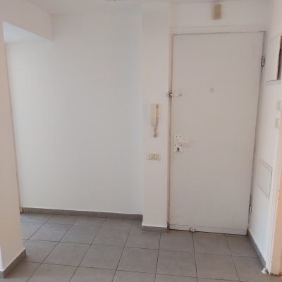 קיר לבן עם דלת לבנה ורצפת אריחים אפורה