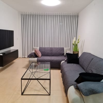 וילון לבן ארוך תלוי על קיר בסלון