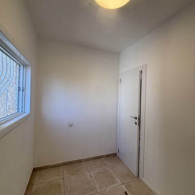 חדר קטן עם רצפת אריחים ודלת לבנה