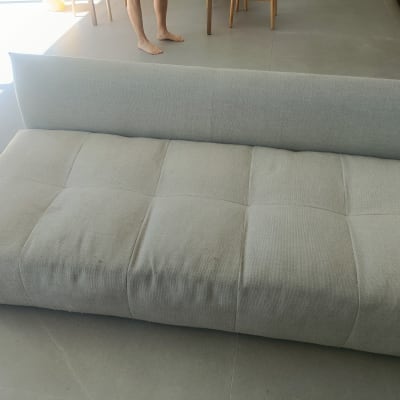 ספה אפורה על רצפת אריחים עם רגליים חשופות