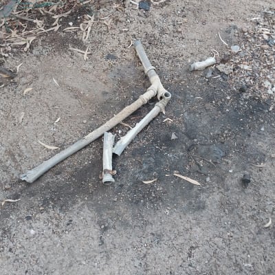 צינורות שבורים על הקרקע ליד גדר