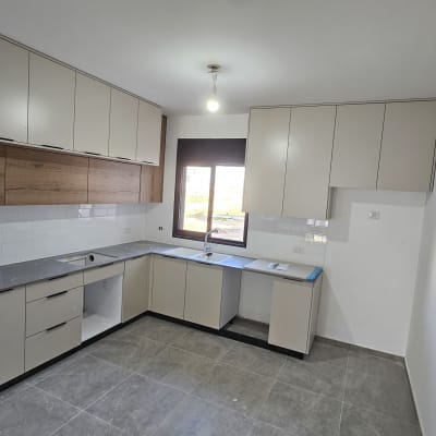 מטבח חדש עם ארונות בהירים ומשטח עבודה אפור