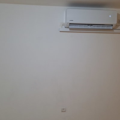 מזגן מותקן על קיר לבן עם שלט רחוק