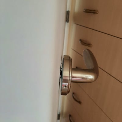 ידית דלת מתכתית מותקנת על דלת עץ