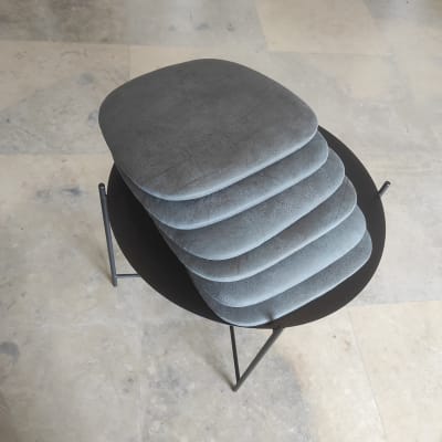 כריות מרופדות אפורות מונחות על שולחן עגול שחור