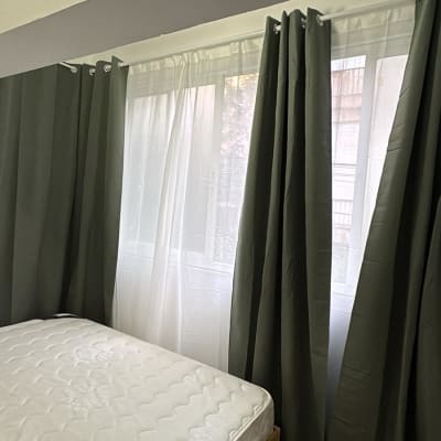 וילונות ירוקים ומיטה בחדר שינה מואר