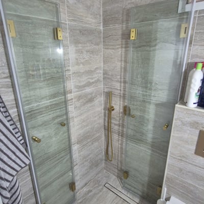 מקלחת עם ראש מקלחת זהוב ודלתות זכוכית