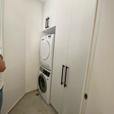 ארון לבן עם ידיות שחורות בחדר כביסה