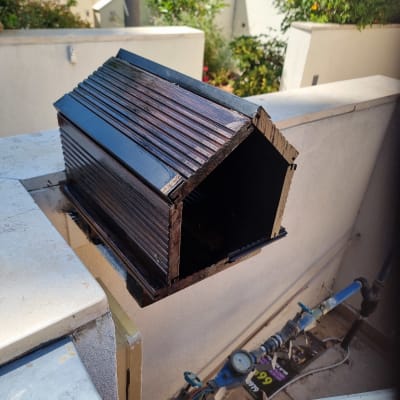 מבנה עץ קטן עם גג משופע, צינור מים עם מד לחץ