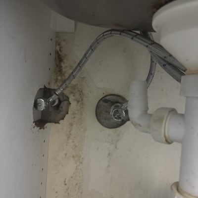 צנרת מתחת לכיור עם סימני רטיבות ועובש