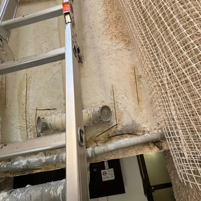 סולם ליד צינורות ואיטום קיר עם רשת