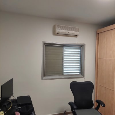 קיר לבן עם חלון ומזגן, כיסא משרדי שחור