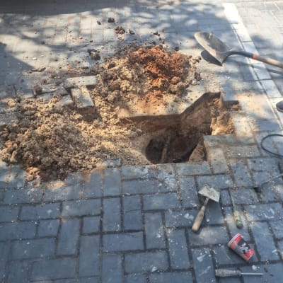 בור פתוח במדרכה עם כלי עבודה של אינסטלטור