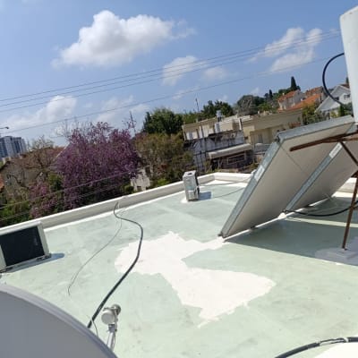 גג עם חומרי איטום לבנים, לוחות סולאריים ודוד שמש