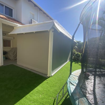 סוכך לבן מחובר לבית עם דשא סינתטי