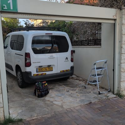 רכב עבודה של טכנאי תריסים לצד תיק כלים וסולם בחנייה