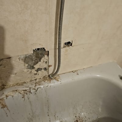 צינור מתכת גמיש בקיר אמבטיה שבור