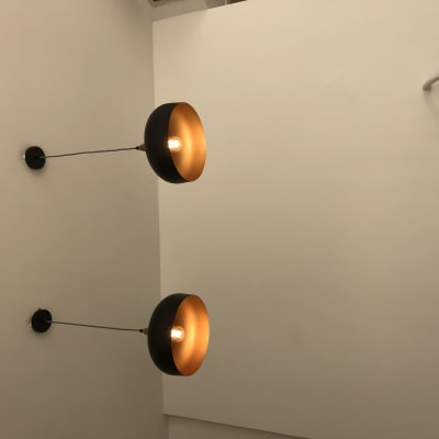 שני מנורות קיר עם נורות דולקות על קיר לבן