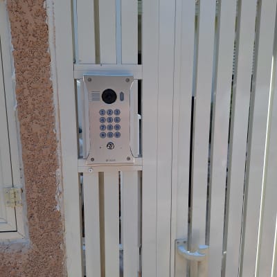 אינטרקום עם מצלמה ומקשים על שער מתכת לבן