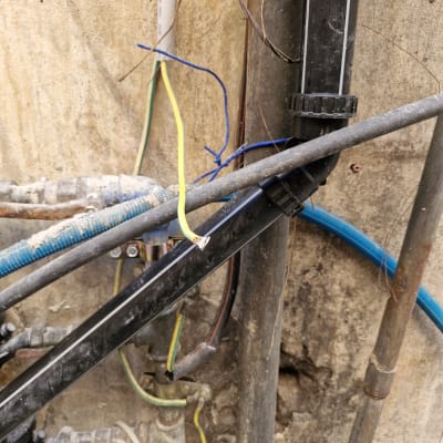 חוטי חשמל חשופים וצינורות על קיר בטון