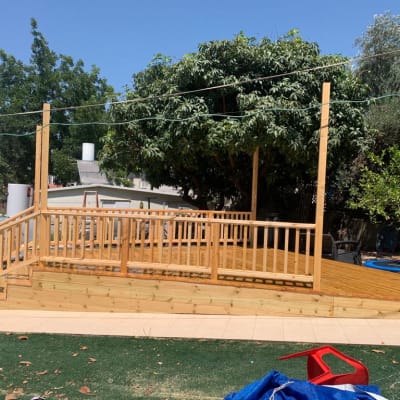 דק עץ עם מעקה בגינה, עצים ברקע