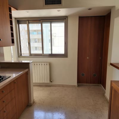 מטבח עם ארונות עץ, כיריים וחלון גדול