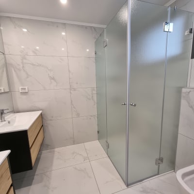 מקלחון זכוכית עם דלתות שקופות בחדר אמבטיה