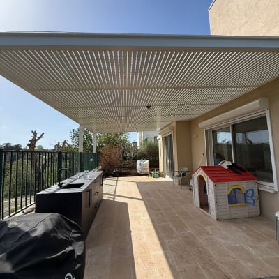 פרגולה מאלומיניום מעל מרפסת עם מטבח חוץ וצעצועים
