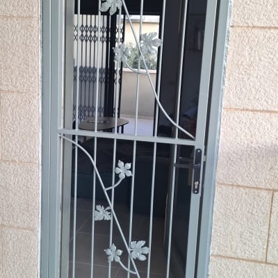דלת ברזל מעוצבת עם עיטורי עלים ממתכת וידית נעילה