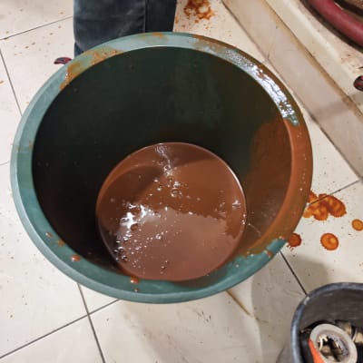 דלי עם נוזל חום ליד צינורות אדומים