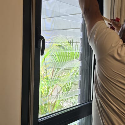 אדם מתקין חלון אלומיניום עם תריסים