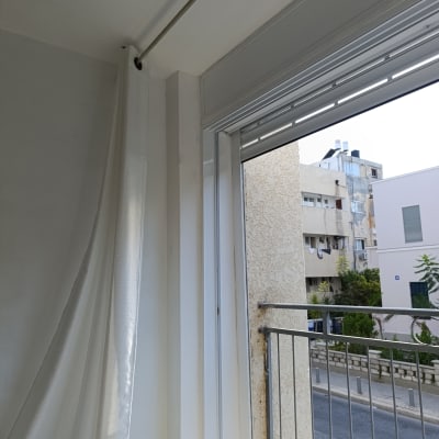 חלון עם וילון לבן ומעקה ברזל