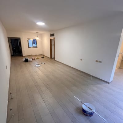חדר ריק עם קירות צבועים ודלי צבע על הרצפה