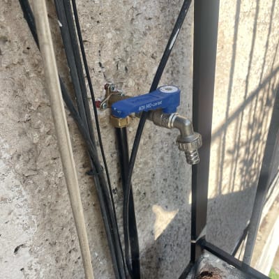 ברז מים כחול מותקן על קיר עם צינור מחובר