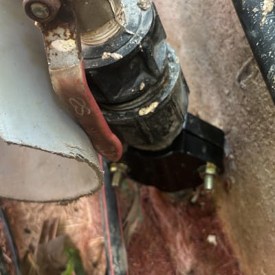 ברז מתכת עם ידית אדומה וצינור מחובר לקיר