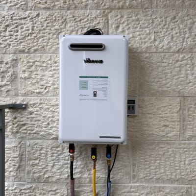 מחמם מים לבן מותקן על קיר עם צינורות צבעוניים