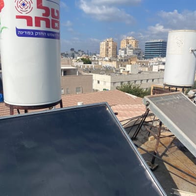 דוד שמש על גג עם רקע של בניינים ושמיים כחולים