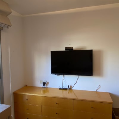 טלוויזיה תלויה על קיר מעל שידה עם מגירות