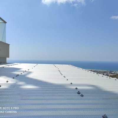 גג מתכת עם ברגים ונוף לים