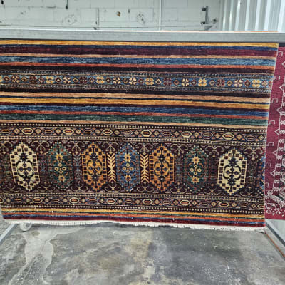 שטיח צבעוני תלוי לייבוש על מתקן מתכת