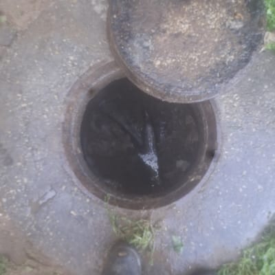 פתח ביוב פתוח עם מכסה מונח בצד