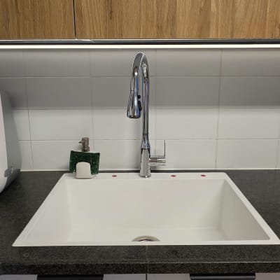 משטח שיש כהה במטבח עם כיור לבן מותקן וברז נירוסטה