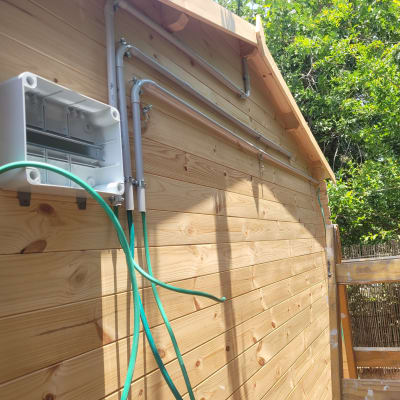 תיבת חשמל פתוחה עם כבלים ירוקים על קיר עץ