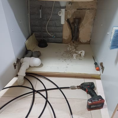 כלי עבודה וצינורות מתחת לכיור במטבח