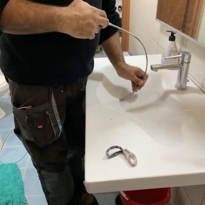 אדם מחזיק כבל מתכת ליד כיור