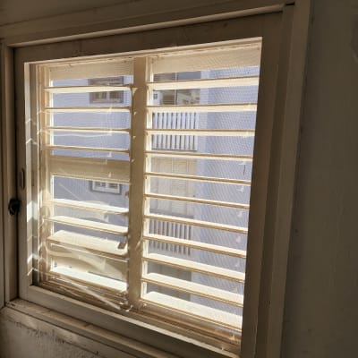 חלון עם תריסים פתוחים חלקית, אור שמש נכנס