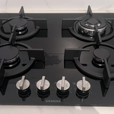 כיריים גז שחורות עם ארבעה מבערים וכפתורי שליטה.